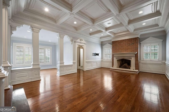 unfurnished living room featuring a brick fireplace, decorative columns, ornamental molding, and beamed ceiling