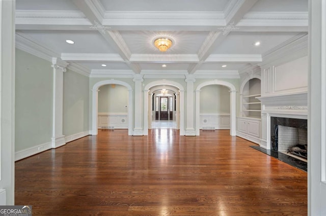 unfurnished living room with decorative columns, built in shelves, a decorative wall, beam ceiling, and a high end fireplace