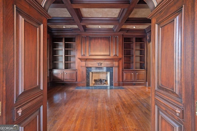 unfurnished living room featuring built in shelves, coffered ceiling, beamed ceiling, and a premium fireplace