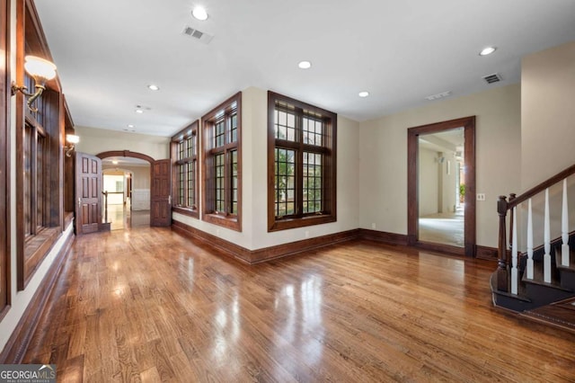 interior space featuring arched walkways, visible vents, and wood finished floors