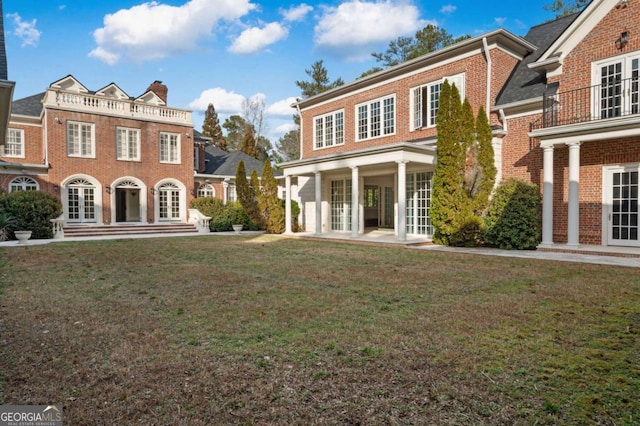 view of front of house featuring brick siding, a front lawn, and french doors