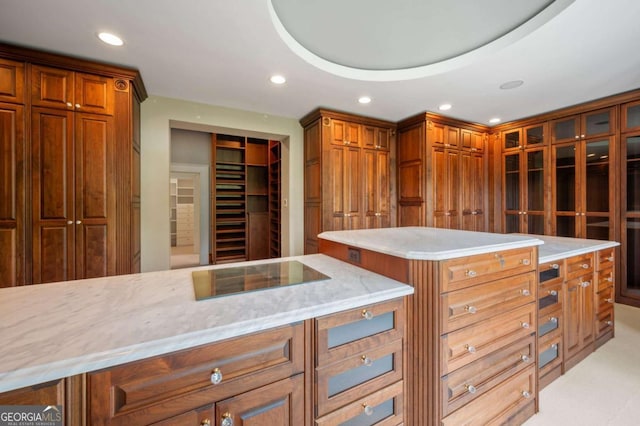 kitchen with black electric stovetop, recessed lighting, a center island, brown cabinetry, and glass insert cabinets