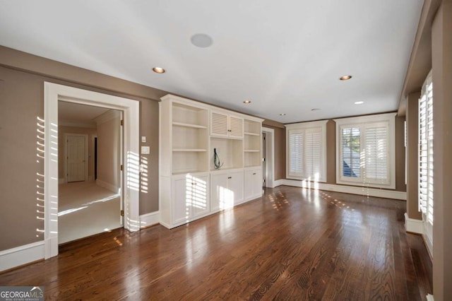 unfurnished living room with dark wood-style floors, ornamental molding, baseboards, and recessed lighting