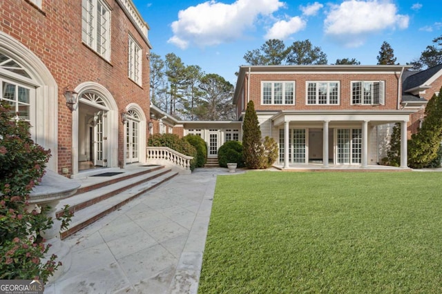 exterior space with brick siding, a lawn, and french doors