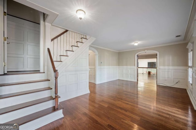 interior space with visible vents, arched walkways, wood finished floors, and ornamental molding