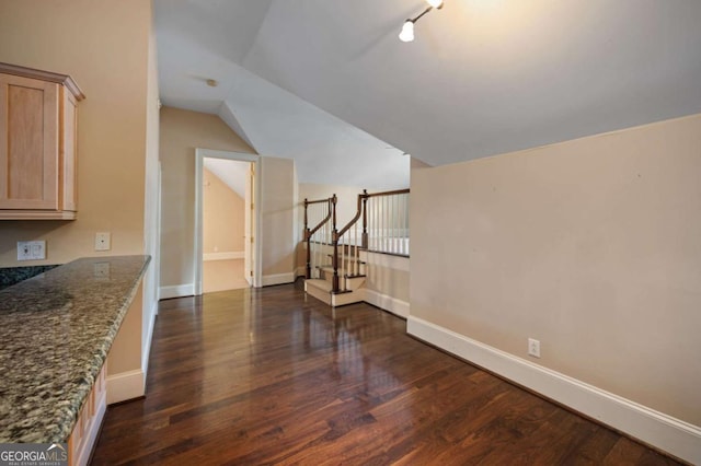 additional living space with lofted ceiling, dark wood-style floors, baseboards, and stairway