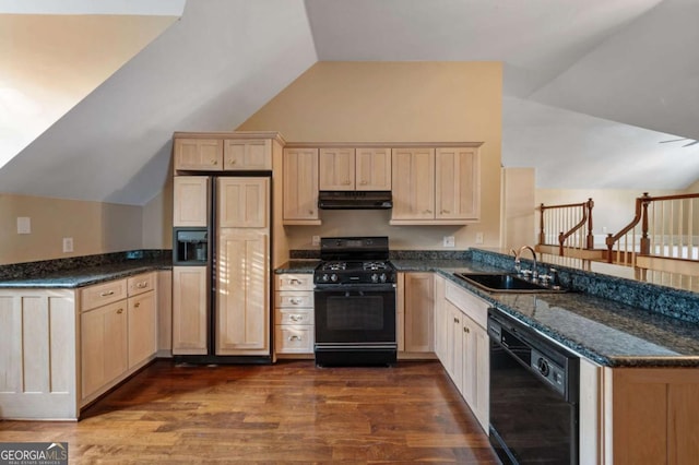 kitchen featuring dark stone counters, lofted ceiling, a peninsula, under cabinet range hood, and black appliances