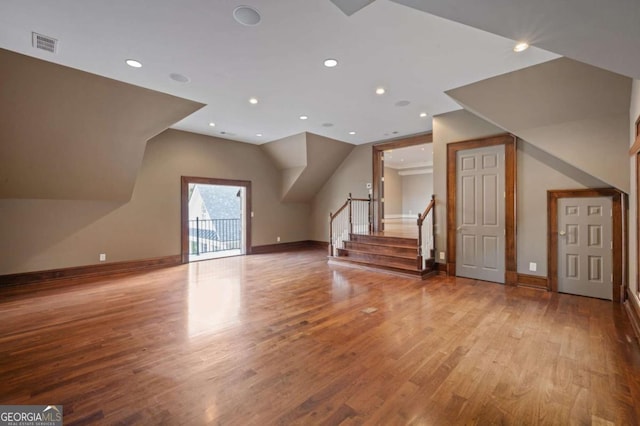 bonus room with light wood-type flooring, stairway, baseboards, and visible vents