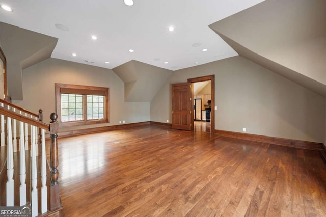 additional living space with baseboards, vaulted ceiling, wood finished floors, and recessed lighting