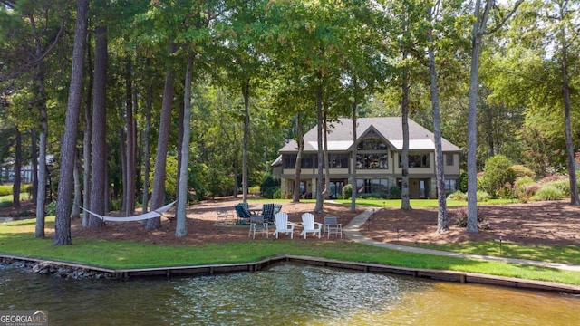 back of property with a water view and a lawn