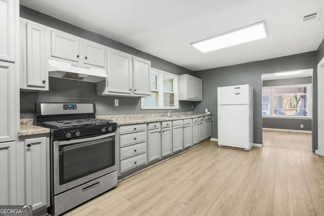 391 Mount Zion Rd SW, Atlanta, GA 30354 - kitchen with stainless steel gas range oven, baseboards, light wood-style flooring, freestanding refrigerator, and under cabinet range hood