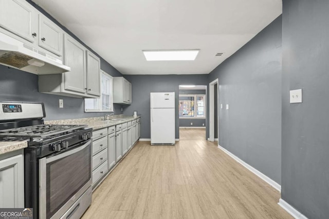 391 Mount Zion Rd SW, Atlanta, GA 30354 - kitchen with light wood-style flooring, freestanding refrigerator, light countertops, under cabinet range hood, and stainless steel range with gas stovetop