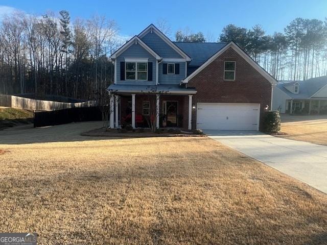 view of front of home featuring an attached garage, brick siding, fence, concrete driveway, and a front lawn