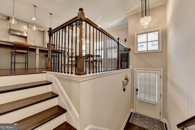 stairway with baseboards, ornamental molding, and a chandelier