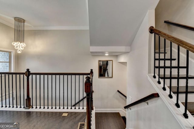 stairway with visible vents, baseboards, ornamental molding, wood finished floors, and a chandelier