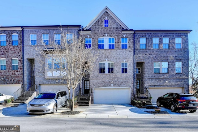 view of front of home with stairs, concrete driveway, and brick siding