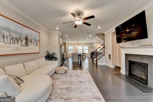 living room featuring ornamental molding, a fireplace with raised hearth, dark wood finished floors, and stairway