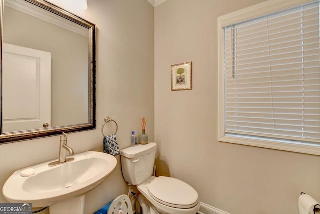 half bathroom featuring baseboards, a sink, and toilet