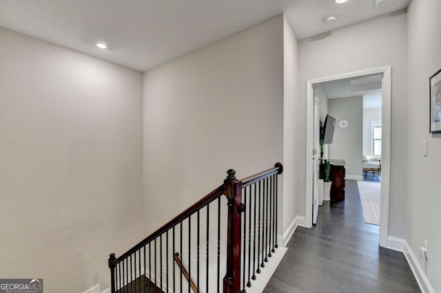 hallway with dark wood-style floors, an upstairs landing, and baseboards