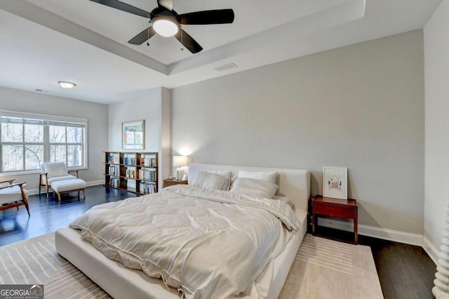 bedroom featuring dark wood-style floors, visible vents, baseboards, and a raised ceiling