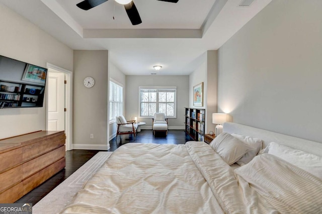 bedroom with ceiling fan, dark wood-type flooring, a raised ceiling, and baseboards