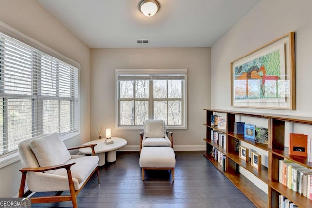 sitting room with dark wood-type flooring, visible vents, and baseboards