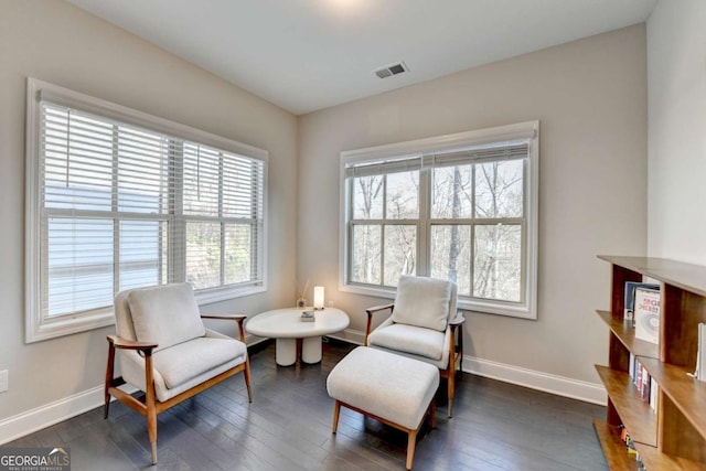 living area with dark wood-type flooring, visible vents, and baseboards