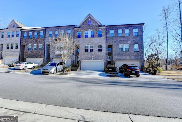 view of building exterior with a garage, concrete driveway, and stairway