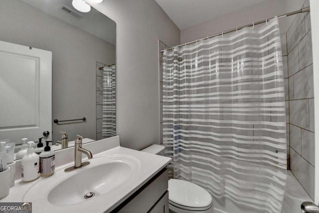 full bathroom featuring a shower with shower curtain, visible vents, vanity, and toilet