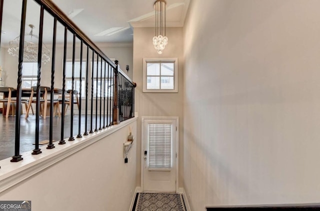 stairway with ornamental molding, an inviting chandelier, and baseboards