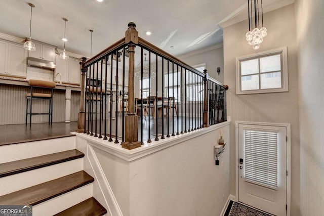 stairway with an inviting chandelier, baseboards, crown molding, and recessed lighting