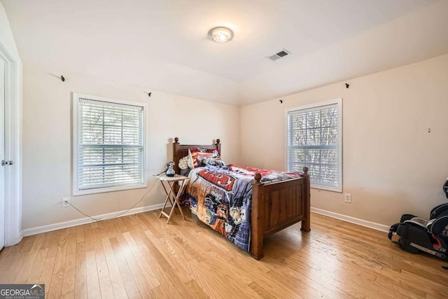 bedroom featuring multiple windows, light wood-style flooring, and baseboards