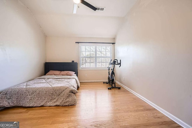 bedroom with visible vents, a ceiling fan, vaulted ceiling, wood finished floors, and baseboards