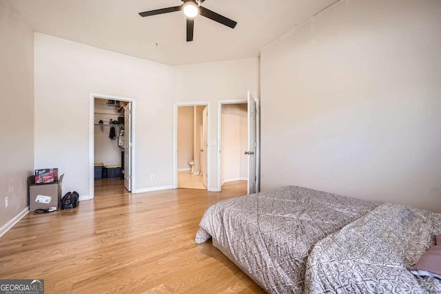 bedroom featuring a closet, a spacious closet, ceiling fan, light wood-type flooring, and baseboards