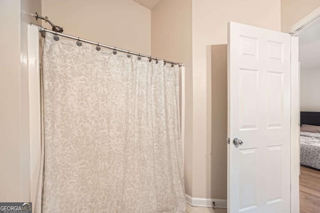 bathroom featuring a shower with curtain, baseboards, and wood finished floors