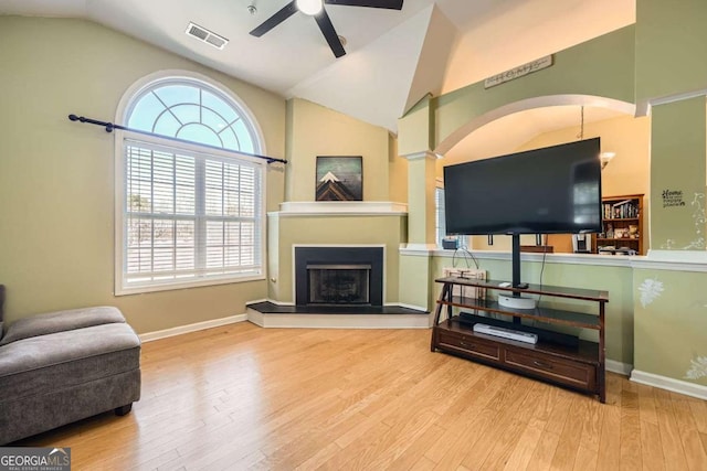 living area with a ceiling fan, visible vents, vaulted ceiling, and wood finished floors