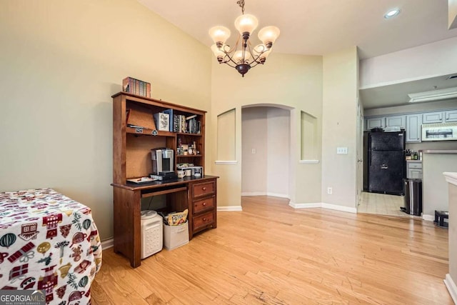 home office with light wood-style floors, baseboards, arched walkways, and a chandelier