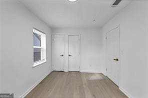 unfurnished room with light wood-type flooring and baseboards