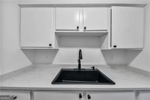 kitchen with white cabinetry, light countertops, and a sink