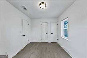 interior space with dark wood-style floors, visible vents, and baseboards