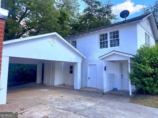 view of front of property with concrete block siding, a carport, and concrete driveway