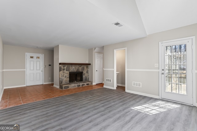 unfurnished living room with baseboards, a fireplace, and visible vents