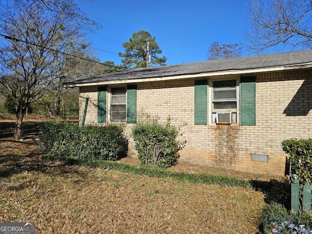 view of side of home with brick siding, crawl space, cooling unit, and a lawn