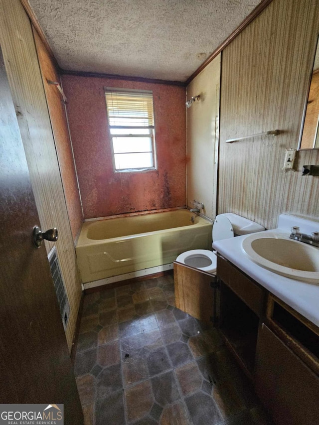 bathroom with a textured ceiling, shower / bathing tub combination, toilet, and vanity