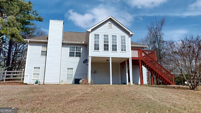 back of property featuring a lawn, fence, stairway, a shingled roof, and a chimney