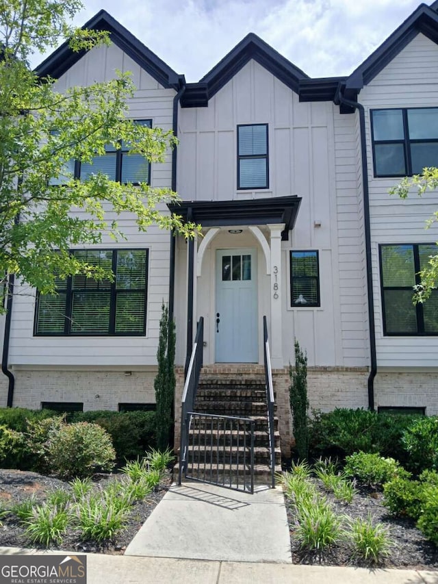 view of front facade featuring entry steps, board and batten siding, and brick siding