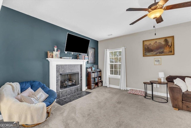 carpeted living area with a ceiling fan, baseboards, and a tiled fireplace