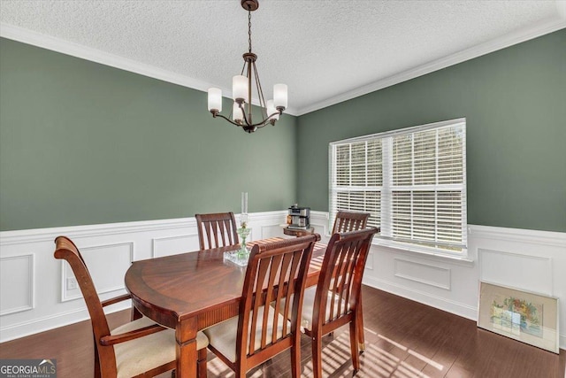 dining area with a wainscoted wall, a chandelier, dark wood finished floors, and a textured ceiling