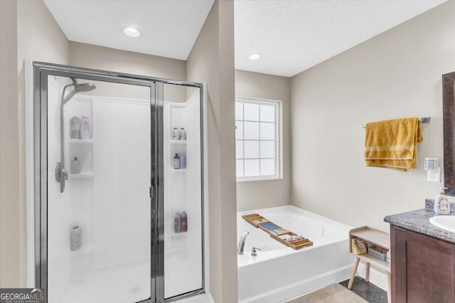 full bath featuring a stall shower, a textured ceiling, a bath, and vanity