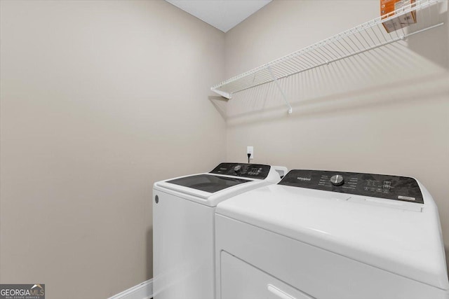 clothes washing area featuring laundry area, baseboards, and washing machine and clothes dryer